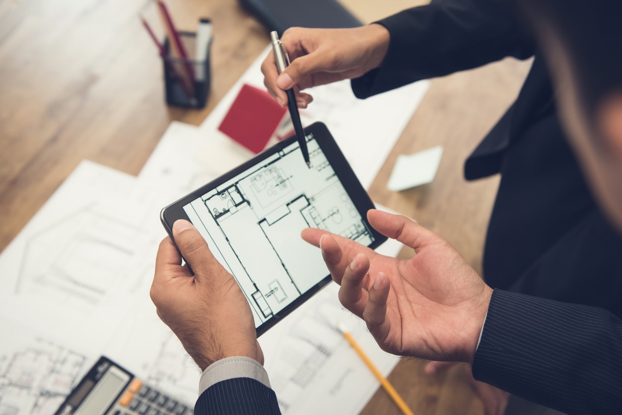 Two hands holding a tablet displaying a home floor plan, illustrating kitchen and bath remodeling