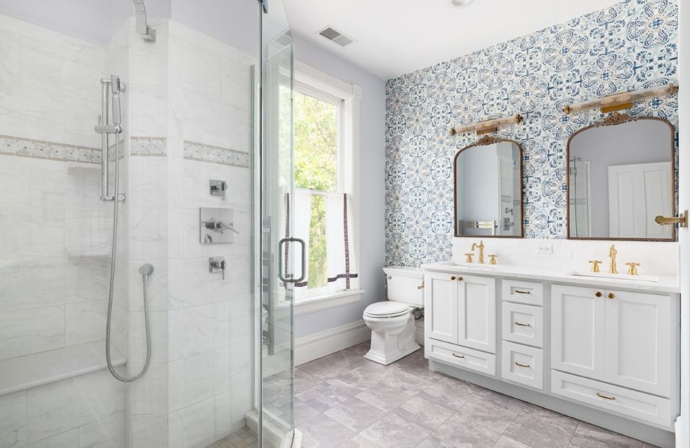 Newly remodeled bathroom in Schaumburg featuring a glass shower enclosure, patterned wallpaper, and double vanity