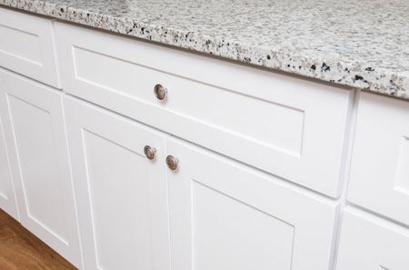 Close-up of newly refaced white kitchen cabinets and granite countertop, showcasing DreamMaker’s cabinet refacing services in St. George