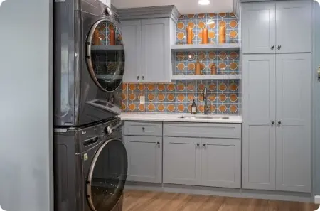 Newly remodeled laundry room featuring gray cabinets, white countertops, and decorative tile backsplash in St. George