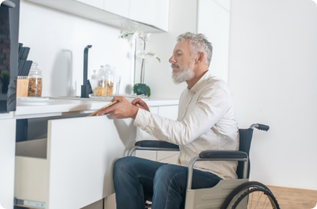 Man in a wheelchair using an accessible kitchen in St. Louis Park, with lowered countertops and an open layout